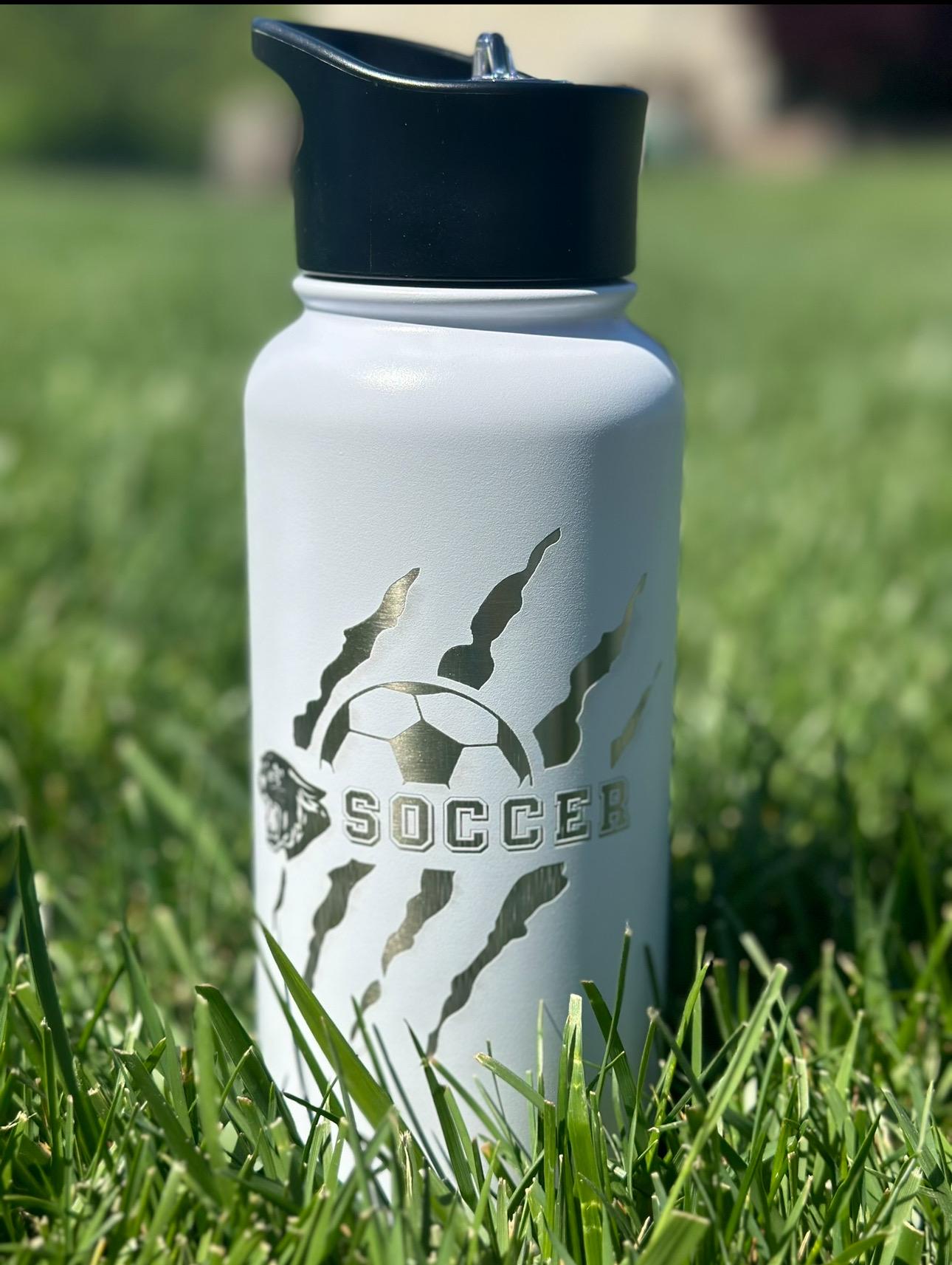 May include: White stainless steel water bottle with a black lid and a silver soccer ball design. The design includes the word &#39;SOCCER&#39; and claw marks around the ball.
